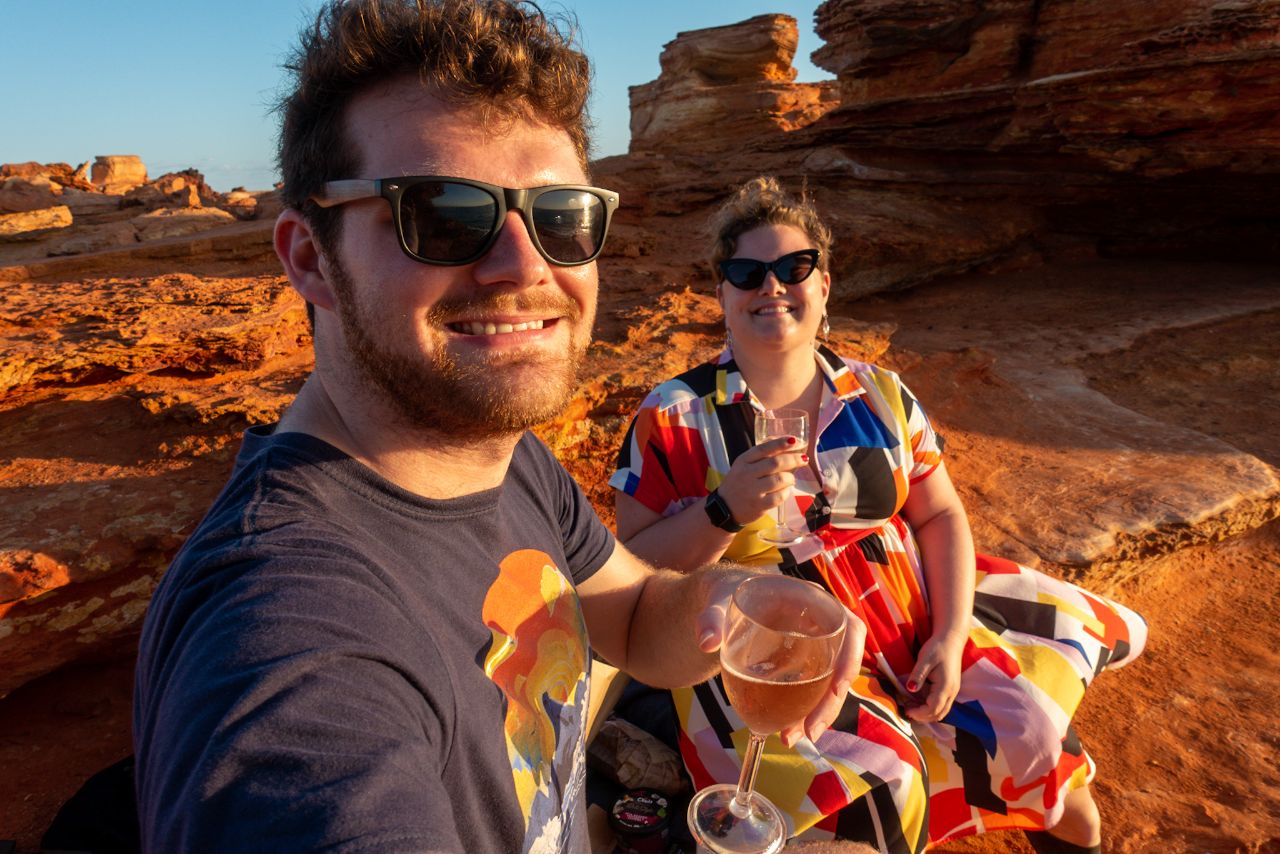 Rocky and Grace with wine glasses against some extremely red rocks and an extremely blue sky